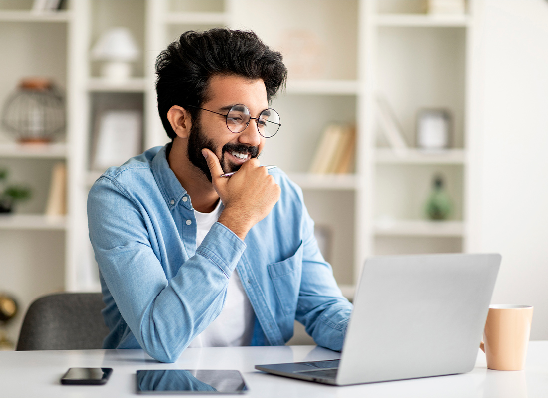 Blog - Smiling Man Working Online With a Laptop at Home in an Office